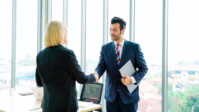 Mand and woman shacking hands in a office building.