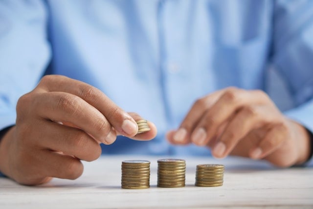 Man with blue shirt stacking coins.